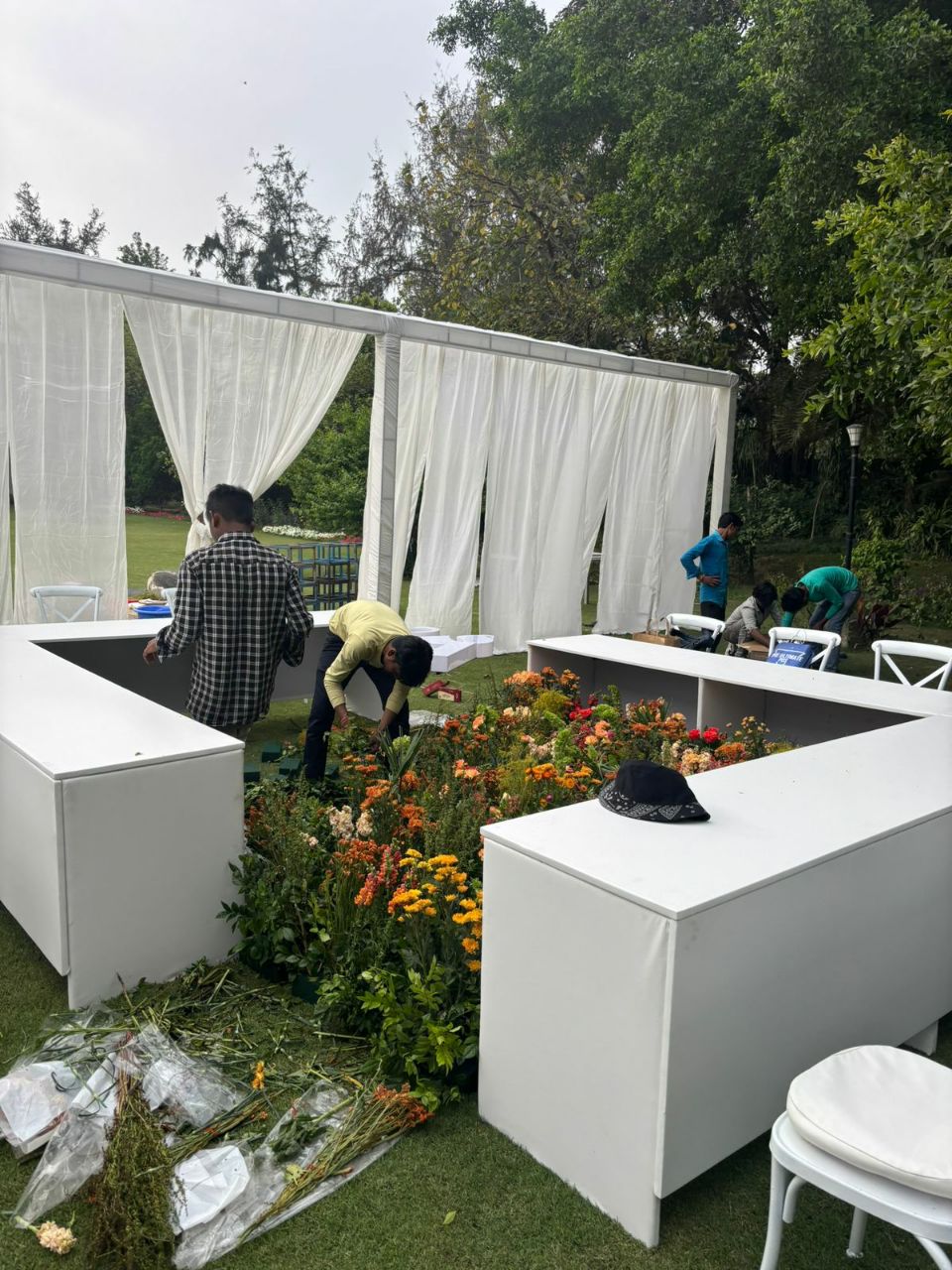Daytime build — floral trough installation under white drape